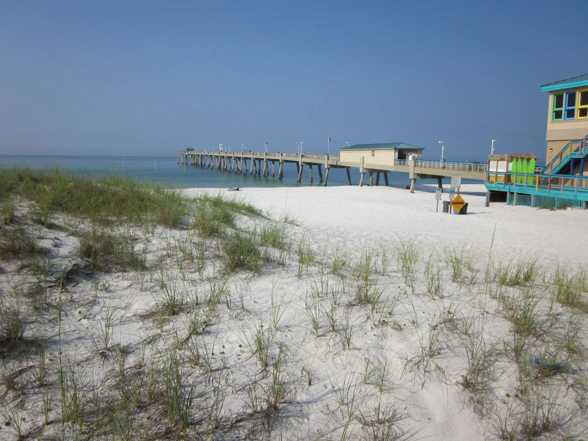 Sea oats on white dunes in front of the Okaloosa Island Pier reaching into the Gulf