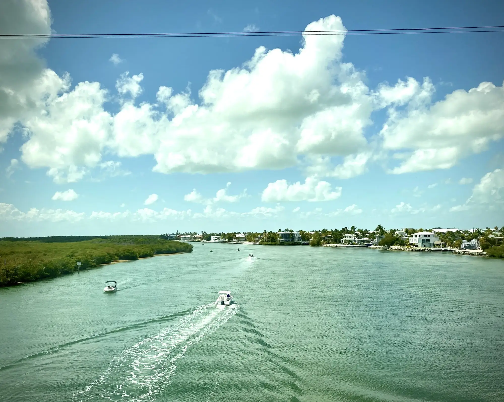 Boats running down the wide green water of Snake Creek in Islamorada