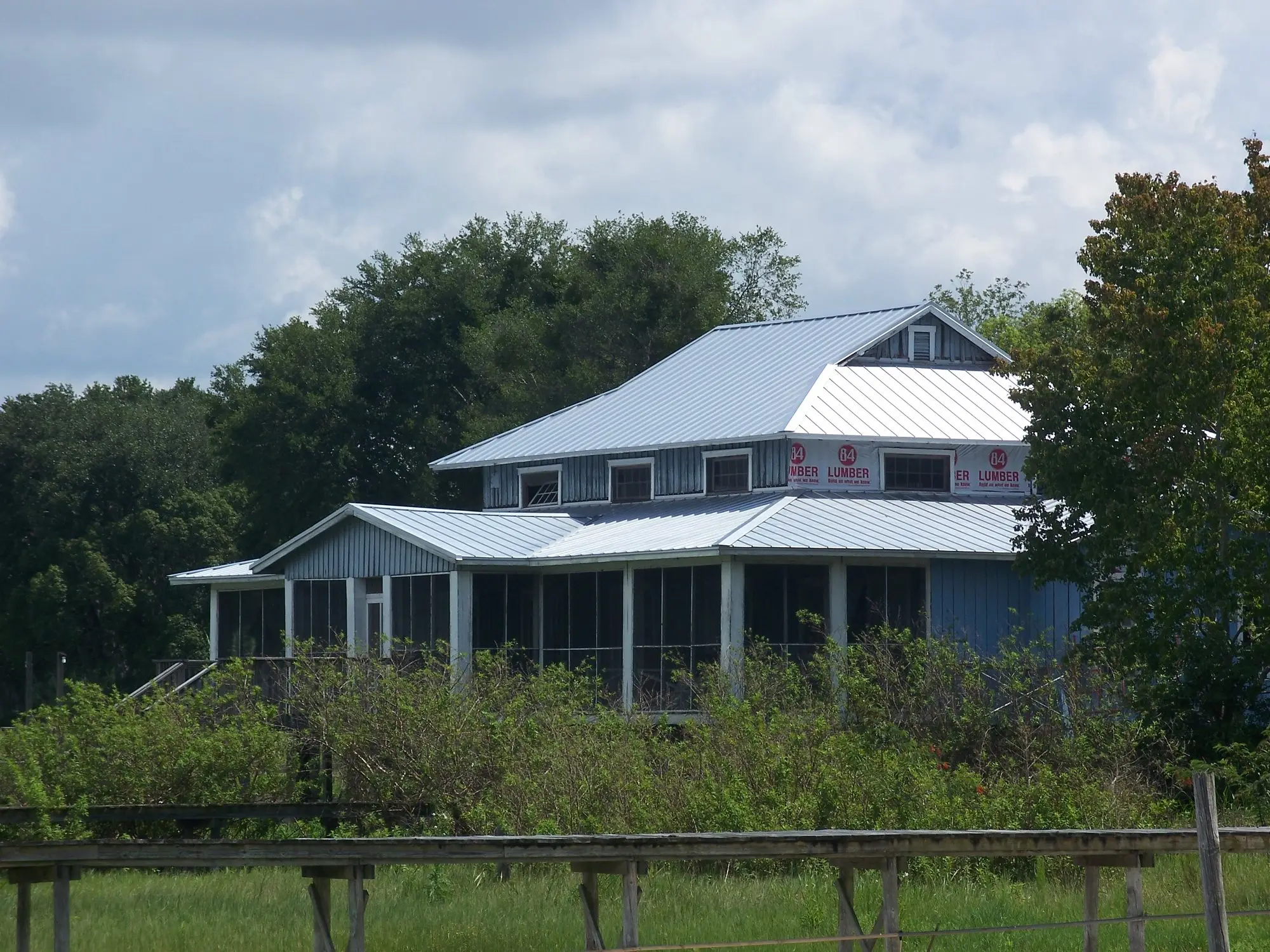 Lake Weir Yacht Club building with a metal roof seen across a lakeside lawn