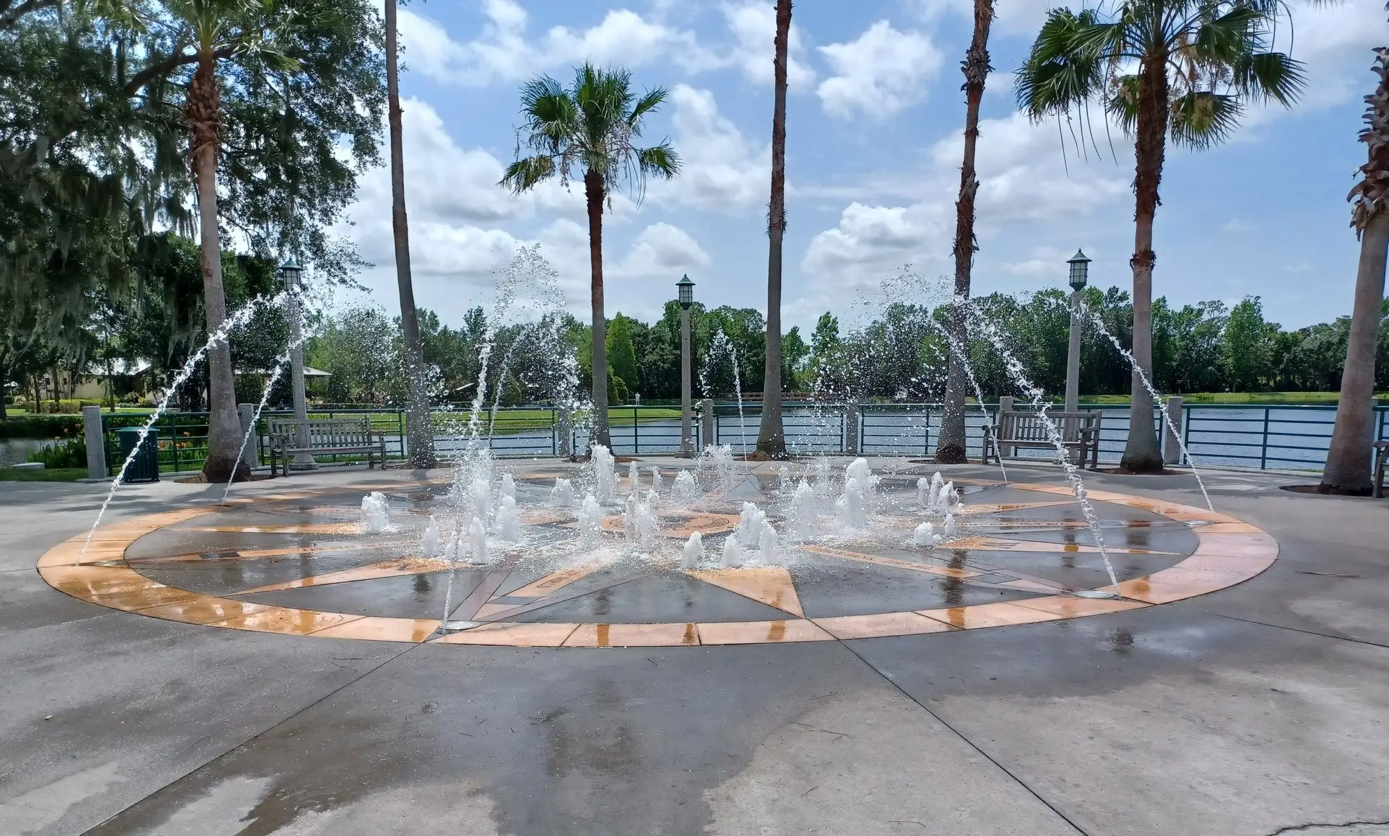 Splash fountain on the Celebration lakefront lined with palm trees under a summer sky