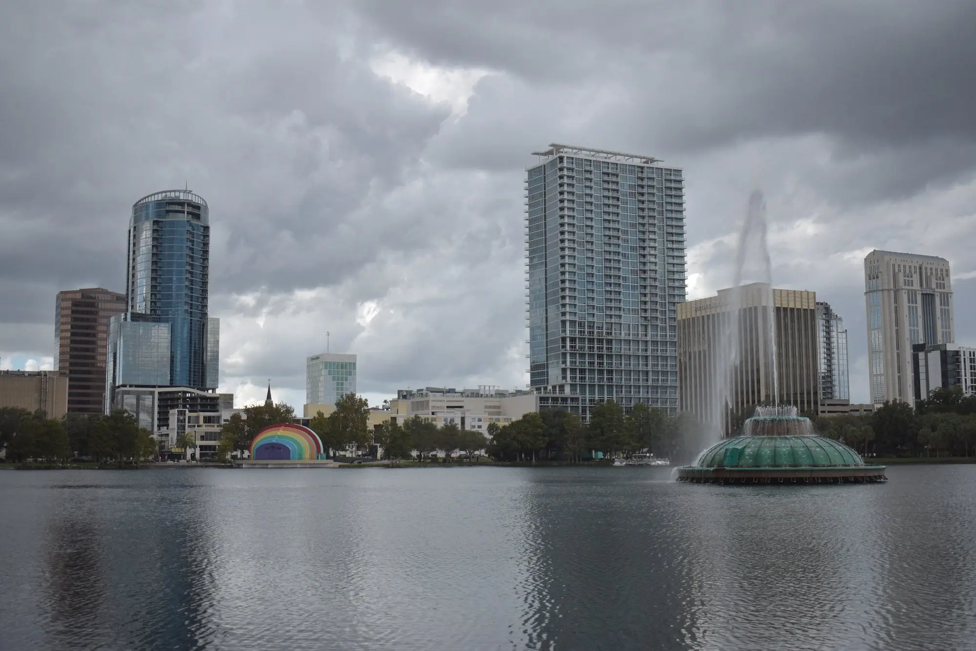 Downtown Orlando high-rises and the Lake Eola fountain reflected in the lake under clouds