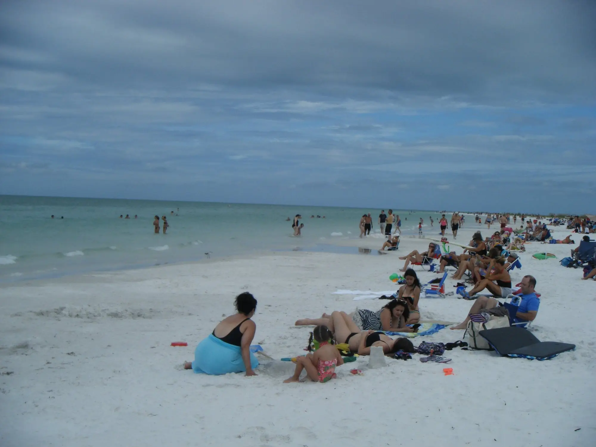 Wide white sand and pale green Gulf water stretching north along Siesta Beach
