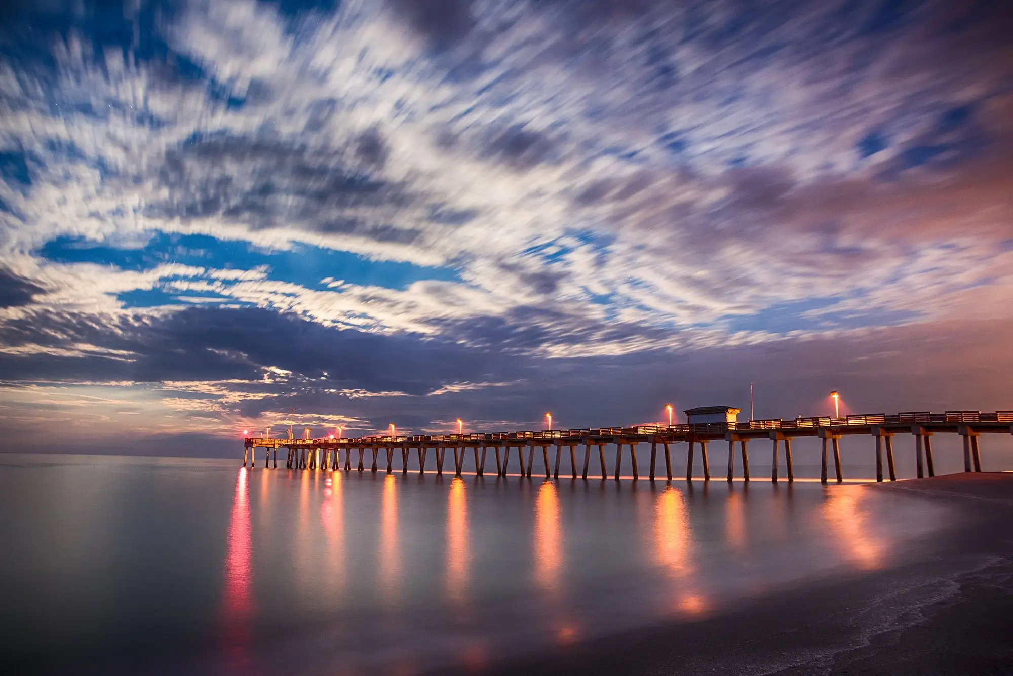 The Venice Fishing Pier stretching into the Gulf at dusk with its lights reflecting on the water
