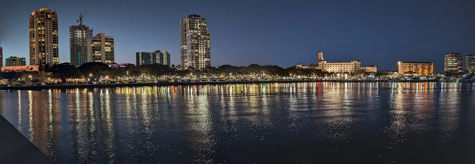 The downtown St. Petersburg skyline lit up at night and reflected in Tampa Bay