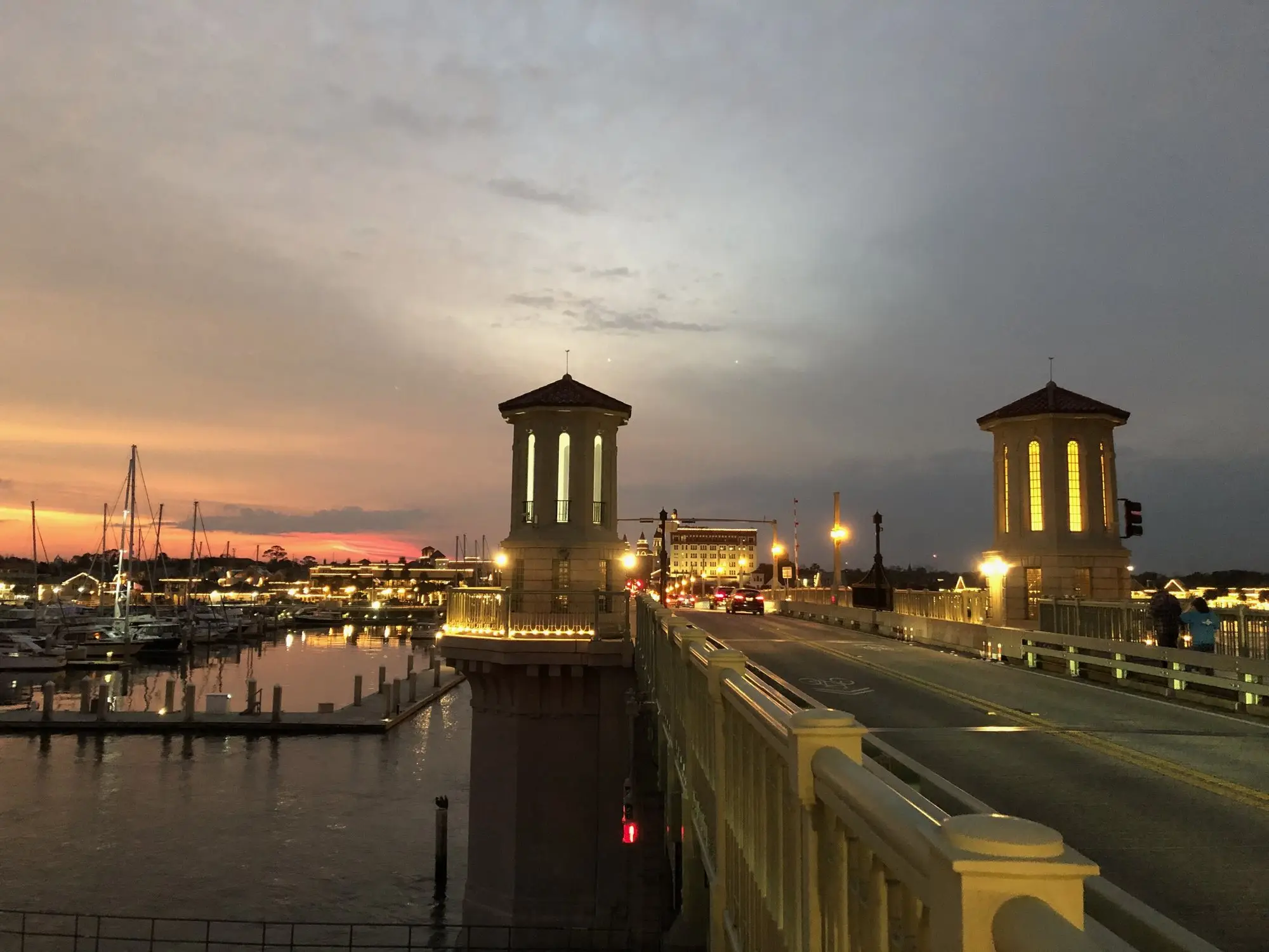 The Bridge of Lions towers lit at sunset with the St. Augustine marina and bayfront behind