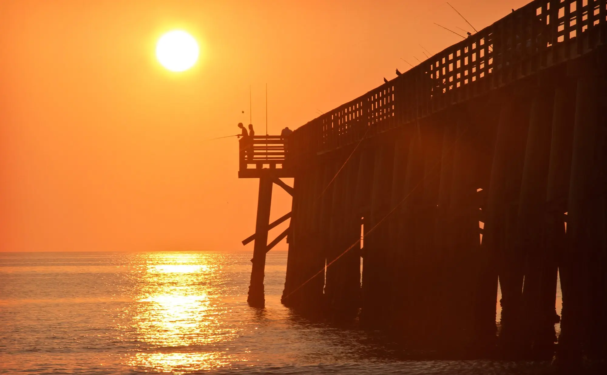 The Flagler Beach pier silhouetted against an orange sun low over the Atlantic