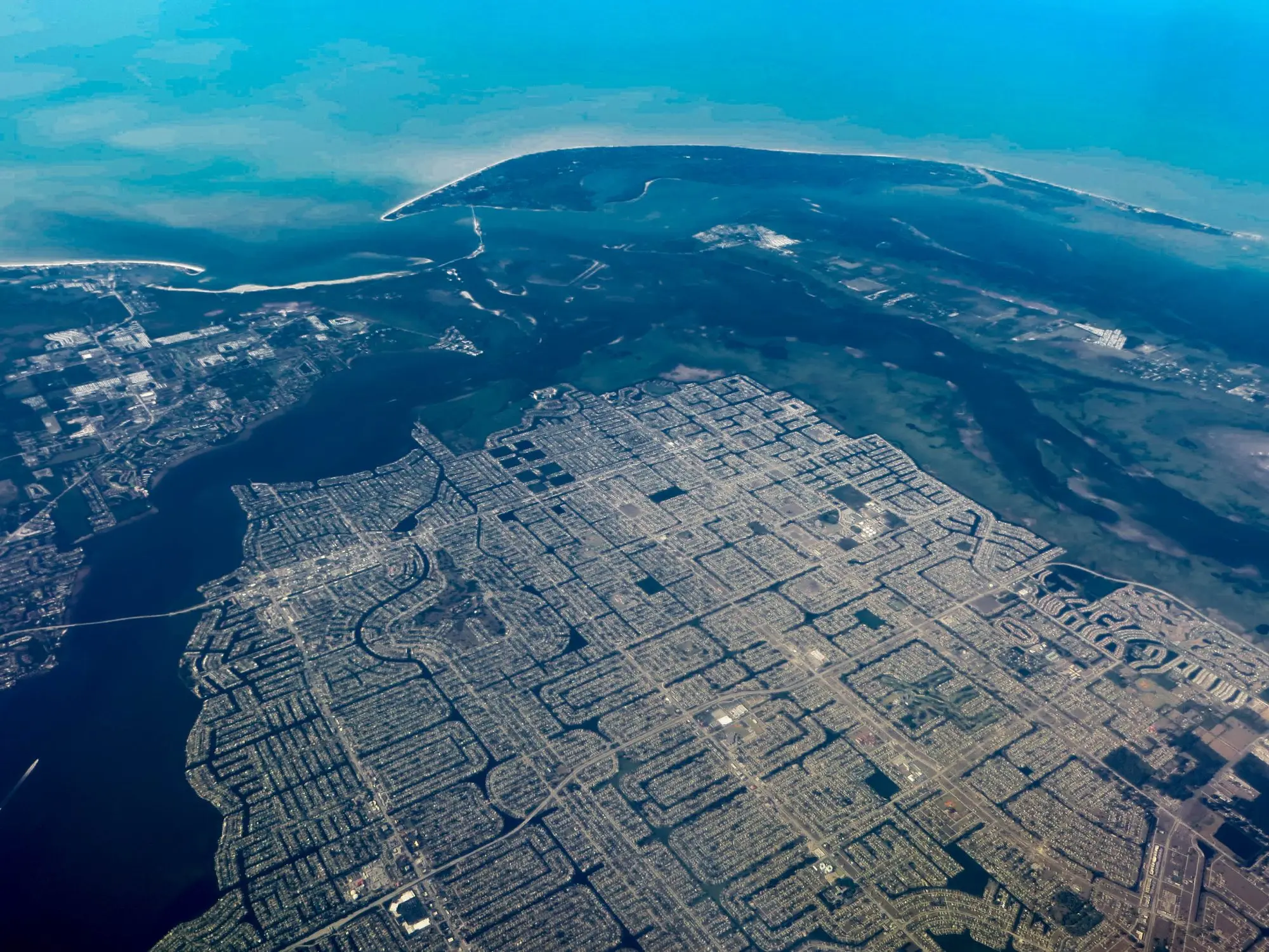 Aerial view of Cape Coral's grid of residential canals where the Caloosahatchee River meets the Gulf