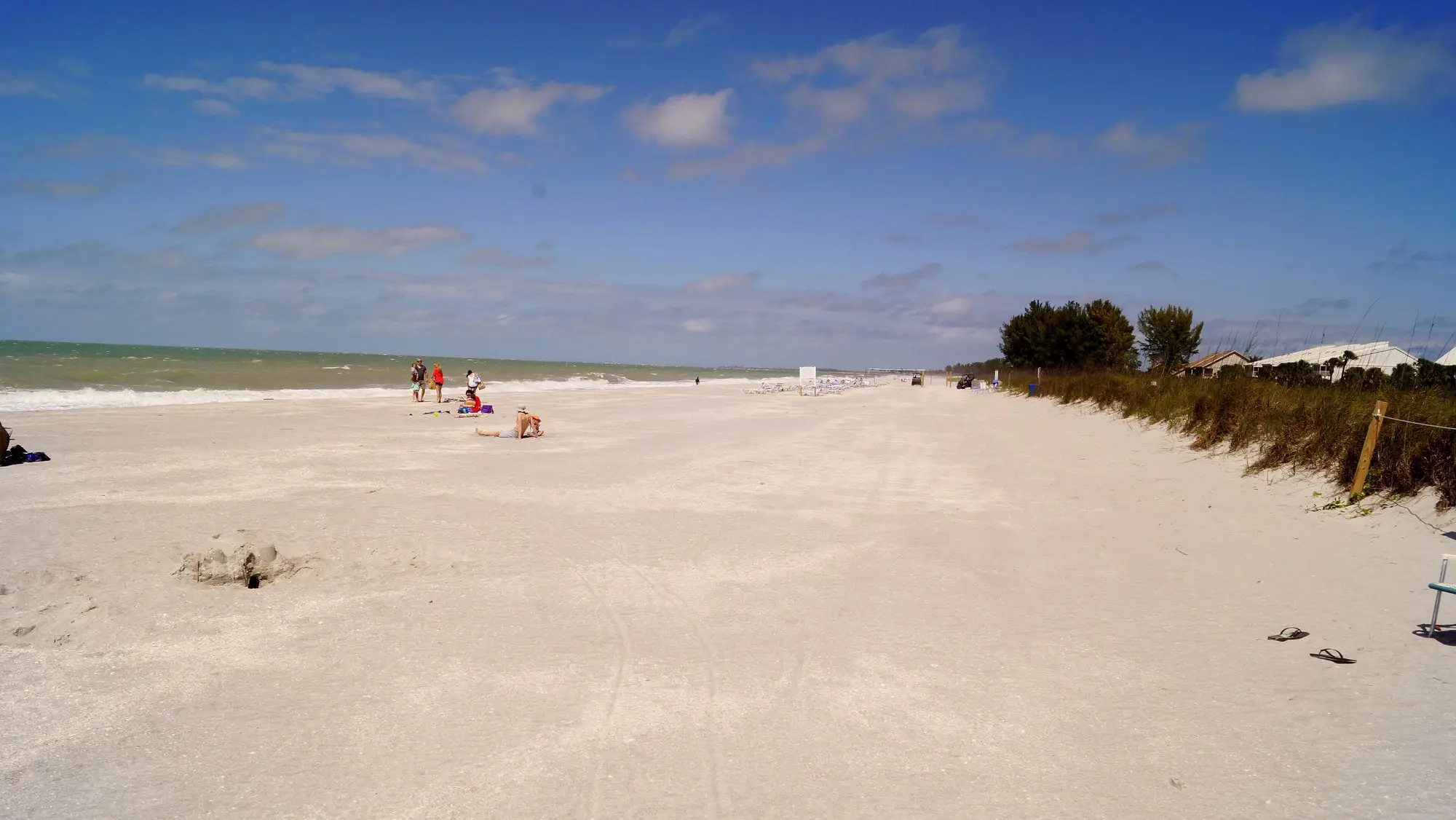 Wide white-sand beach on Captiva Island with sea grape and calm Gulf water under a blue sky