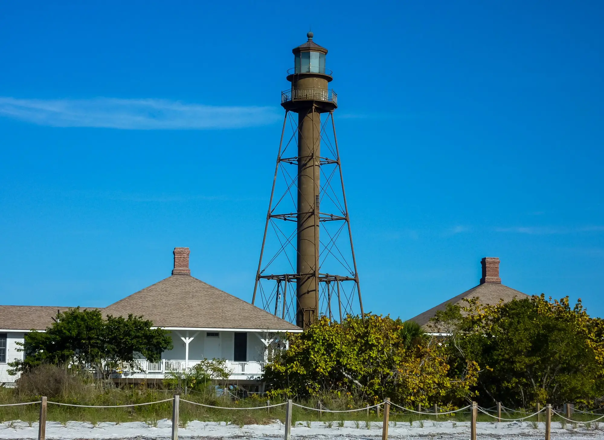 The iron-frame Sanibel Lighthouse and its keepers' cottages under a bright blue sky